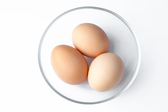 brown eggs in glass bowl on white background