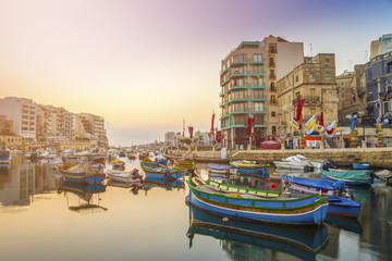 St.Julian's, Malta - Traditional colorful Luzzu fishing boats at Spinola bay at sunrise - obrazy, fototapety, plakaty