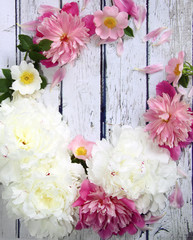 A beautiful wreath of peony and dog rose flowers on a wooden background, rustic style