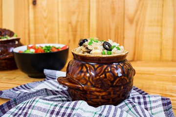 Rice with chicken, mushrooms and olives on wooden background