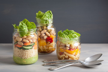 vegan couscous and pasta salad in mason jars with vegetables beans