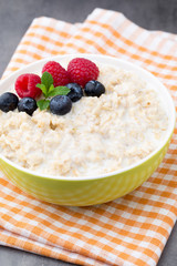 Oatmeal porridge in bowl with berries raspberries and blackberries.