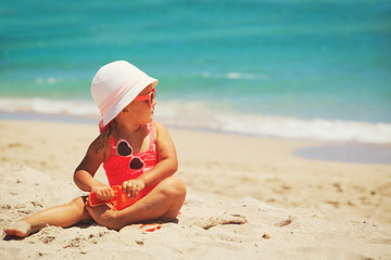 cute little girl play with sand on beach