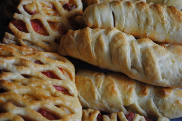 Sausage in the dough sprinkled with sesame seeds on a wooden background in rustic style. 