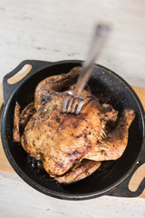 Fork in defocus in fried chicken grill on a black frying pan on a light wooden board