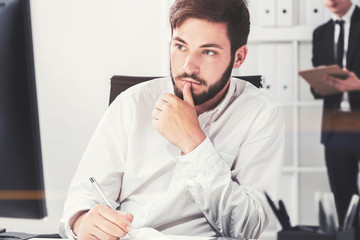 Pensive bearded businessman in a white office