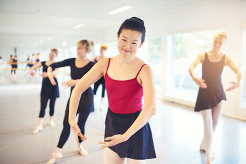 Fototapeta na wymiar Asian adult woman smiling while performing ballet in class