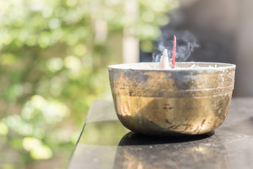 Incense burner with smoke in a metal bowl on stone table