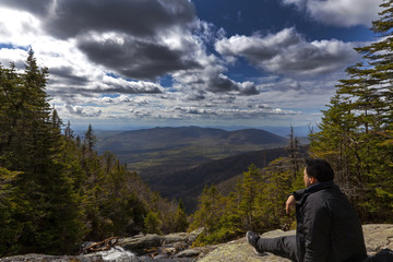 Man sitting and looking out from elevation on Mount Washinton via Ammonoosuc ravine trail - 161974769