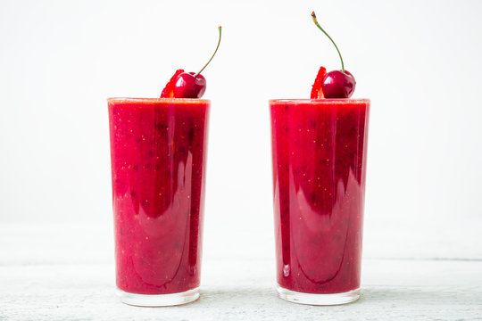 Cherry smoothie and tasty berries on glass on white background. Fresh natural milkshake