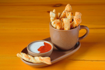 Bread sticks in cup with garlic and tomato sauce