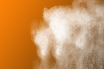 White powder explosion on orange background.