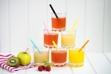 Collage of glasses with fresh delicious smoothie juice and straw on board background colourful for kids party