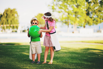 Fototapeta premium Two funny kids in green park. Little boy and girl ready to go to the pool on a hot summer day