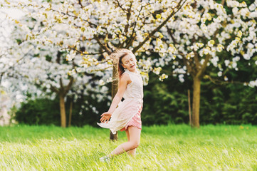Naklejka na ściany i meble Pretty little kid girl dancing in spring blooming garden