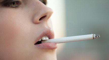 Naklejka premium Woman with a cigarette. A smoking girl in a smoke close up. Young beautiful model