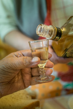 Old woman serving traditional alcoholic beverage - hungarian palinka