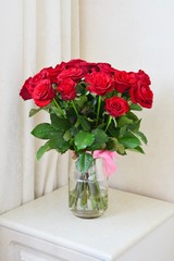 Red roses bouquet  in glass vase on white table