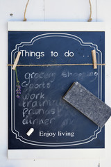 Black chalk board with a to do list with white chalk writing and a sweeper to wipe away to much tasks to avoid a stressed burn-out
