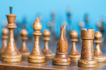 Vintage wooden chess pieces on an old chessboard.