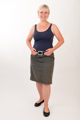portrait of a attractive blond haired mid aged european woman wearing green skirt and blue top showing happy face - full body - studio shot on white background.