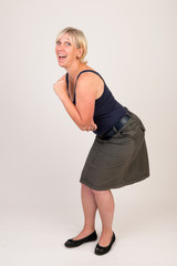 portrait of a attractive blond haired mid aged european woman wearing green skirt and blue top showing happy face - full body - studio shot on white background.