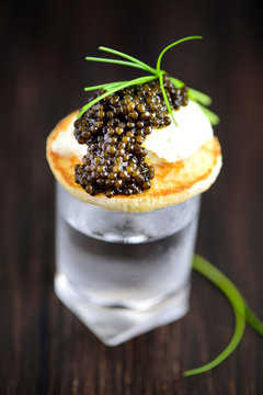 Russian Pancakes Blini with Sour Cream and Black Caviar Served on Vodka Shot.