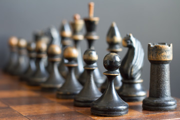 Vintage wooden chess pieces on an old chessboard.