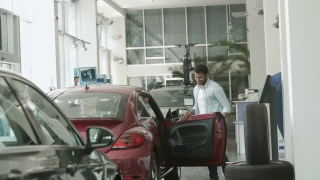 Pretty girl asks the boyfriend to buy her a car in car showroom