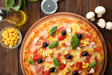 Plate with tasty pizza, its ingredients and knife on wooden table