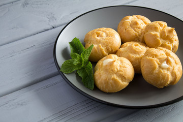 Eclairs on the grey plate on the wooden background