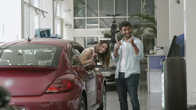Young man and woman bought a car in car showroom