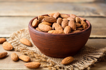 Almonds in ceramic bowl on wooden background
