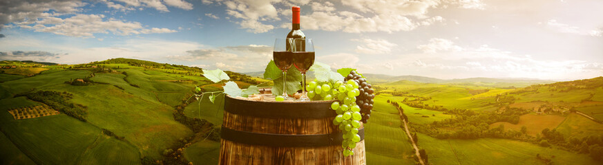 Fototapeta na wymiar Red wine with barrel on vineyard in green Tuscany, Italy