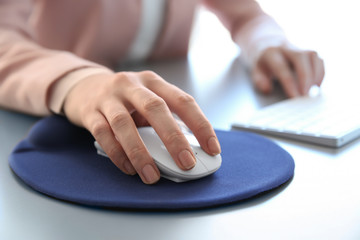 Female hand holding computer mouse on pad