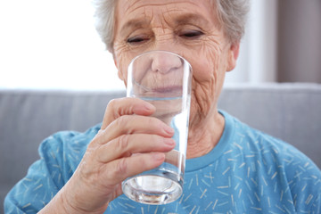 Elderly woman drinking water at home. Concept of retirement