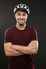 Handsome young bicycle rider with helmet on dark background