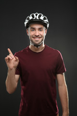 Handsome young bicycle rider with helmet on dark background