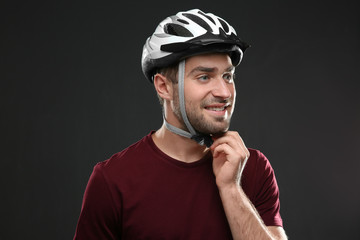 Handsome young bicycle rider with helmet on dark background