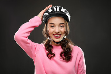 Beautiful young bicycle rider with helmet on dark background