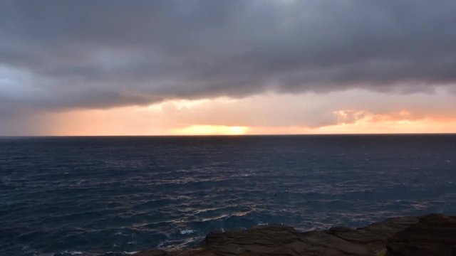 Time lapse sunrise through rain clouds over ocean in Oahu
