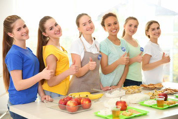 Young volunteers near table with different products indoors