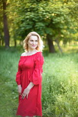 Summer lifestyle portrait of beautiful girl Wearing stylish red dress. Enjoying life and smiling.