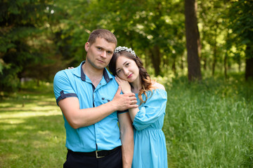 Pregnant couple. Husband touching his wife in nature