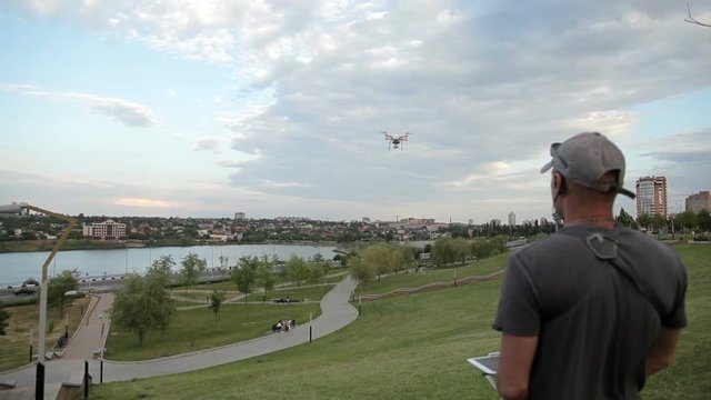 Man operating drone flying or hovering by remote control in nature