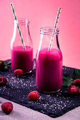 Himbeer Smoothie mit Strohhalm auf Schieferplatte vertical