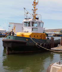 Naklejka premium A tug tied up in the port of Poole Dorset; awaiting the arival of another ship to pilot or help dock in this deep port