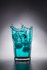 Glass of green water with splash and ice