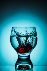 Glass of water with red dice on a gradient background