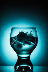 Glass of water with ice on gradient background